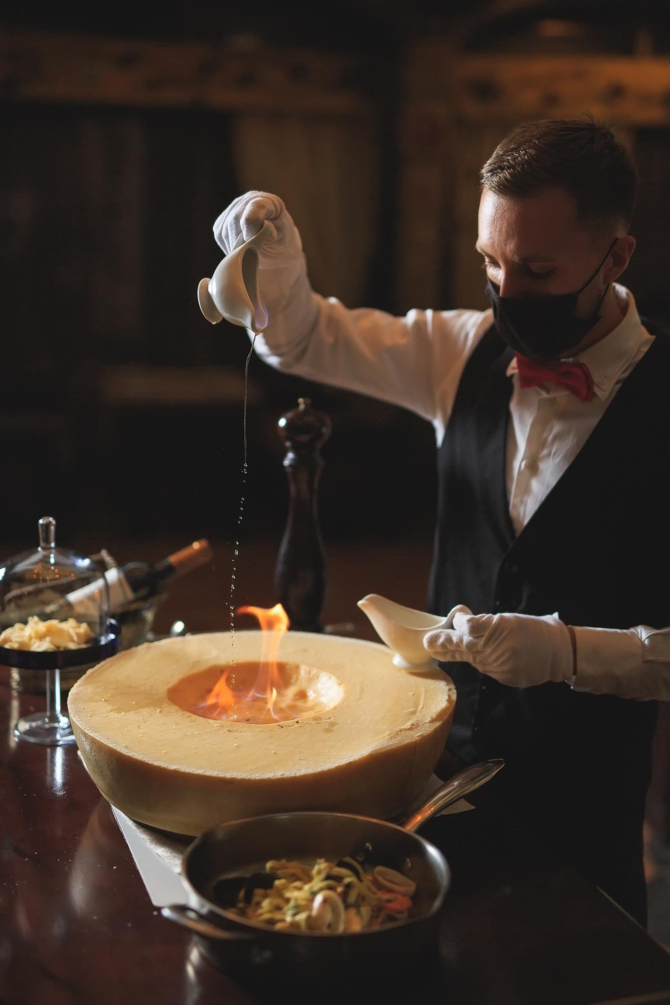 Chef preparing plated tasting menu on dark table